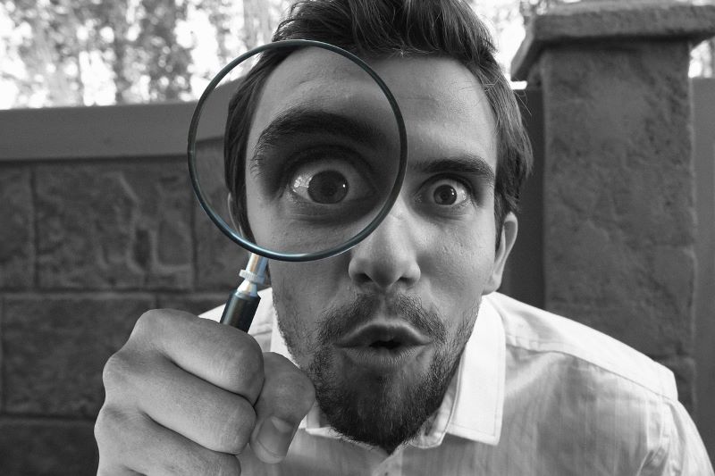 Man looking through magnifying glass