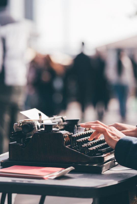 Person writing on typewriter, deciding on alternatives to Amazon self-publishing